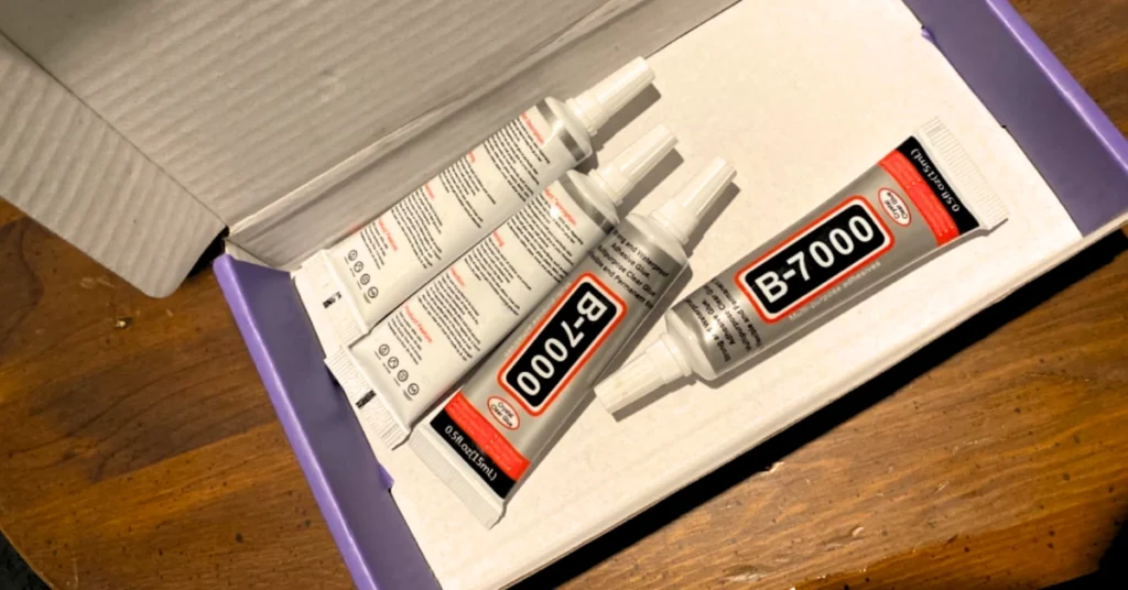 Image of a box containing multiple tubes of B-7000 multipurpose adhesive, known for its industrial-strength bonding, ideal for use on a variety of materials such as glass, metal, and fabric